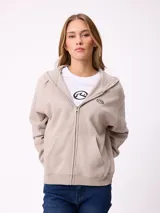 Canguro con cierre frontal de la marca Rusty, en color beige. Presenta capucha, bolsillos tipo canguro y logo bordado en el pecho.