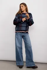 Sweater de punto con diseño de cuadros tartán en escala XL, en tonos azul, negro y bordó. Presenta un corte oversize, cuello redondo y terminaciones con volados en color rosado en el cuello, puños y ruedo.