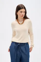 Sweater de tejido de punto fino en color blanco, con cuello redondo a la base y mangas largas de corte holgado.
