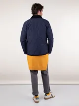 Cazadora acolchada azul marino con cuello de pana negro, cierre con botones a presión y bolsillos laterales.
