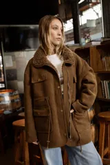 Campera de efecto gamuza color tostado con interior de corderito sintético. Presenta cierre frontal, bolsillos delanteros con solapa, cintura ajustable con cordón y puños con detalle de corderito.