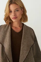 Tapado de largo medio abierto con cuello, confeccionado en lana fina sin teñir con detalles de terminación envivados en los bordes y mangas tres cuartos.