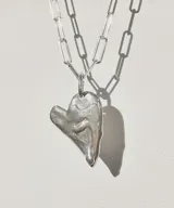 Collar plateado con cadena de eslabones rectangulares y dije irregular con forma de corazón.