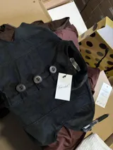 Top de estilo japonés confeccionado en pana negra, con cuello alto y cierre frontal de botones grandes.