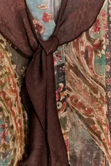 Blusa de manga larga con escote en pico y detalle de lazo frontal. Presenta un diseño estampado estilo paisley en tonos tierra, verdes y rojizos, con corte holgado y puños ajustados.