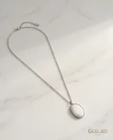Collar de cadena fina de acero con dije ovalado de nácar engarzado en metal plateado.