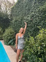 Vestido corto de color verde esmeralda, con escote en pico y breteles finos. Presenta aberturas en los laterales de la cintura y espalda descubierta.