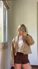 Campera corta de ecocuero color beige, con diseño de solapas y cierre frontal con botones a presión metálicos.