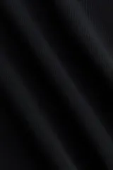 Top entallado negro sin mangas en punto pesado, con escote redondo, pliegues en un lateral y bajo asimétrico.