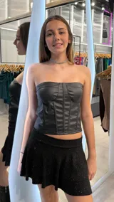 Top tipo corset strapless de cuero sintético negro con varillas verticales.