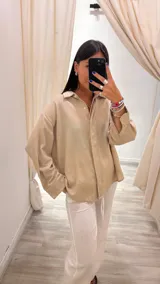 Camisa oversize color verde militar con finas rayas verticales de lurex, cuello camisero y mangas largas con puños anchos.