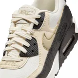 Championes Nike Air Max 90 con diseño clásico, combinando paneles de cuero blanco, beige y detalles en negro con textura de reptil. Cuenta con la icónica unidad de aire visible en el talón y suela de goma resistente.