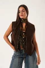 Chaleco marrón de gamuza con cordones laterales y tachas plateadas.