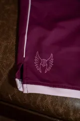 Short deportivo de lycra color bordó con ribete blanco en el ruedo y un pequeño logo estampado en el lateral con un casco alado.