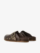 Zueco de cuero liso negro con plantilla anatómica forrada en gamuza, hebilla ajustable de estilo western en metal envejecido y tachas metálicas en el contorno.