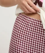 Pijama largo de dos piezas, confeccionado en malla suave con tecnología Peach Touch. Incluye una blusa de manga corta color blanco con estampado frontal de la palabra "LOVE" en tonos pastel y un pantalón de cuadros vichy en color bordó y blanco, con cintura elástica.