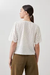 Blusa negra de broderie con escote en V y lazos para atar en el frente. Tiene mangas cortas con terminación de puntilla. 
