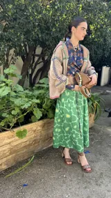 Falda midi de lino 100%, color verde con estampado de flores grandes en tonos de verde más claro y amarillo. Presenta pliegues en la cintura y corte amplio.