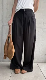 Pantalón negro de lino con pinzas en la cintura, cordón ajustable y corte wide leg.