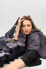 Bolso de gran tamaño confeccionado artesanalmente con técnica de ensamblado de cuadrados de lana merino afiltrada en tonos violeta y gris. Presenta un diseño texturizado y voluminoso, con forro interior de algodón y bolsillo con cierre.