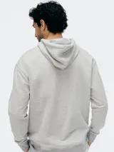 Buzo con capucha de corte clásico, confeccionado en tejido de algodón, con bolsillo frontal tipo canguro y puños acanalados.