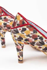 Zapatos de salón de tacón medio, confeccionados en arpillera con estampado multicolor en tonos marrones, granates y ocres. Presentan un diseño estructurado con piezas diferenciadas en puntera, laterales y talonera, unidas por ribetes de terciopelo granate. Cuentan con interior en piel y suela de cuero.