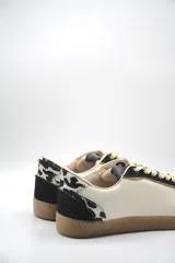 Zapatillas urbanas de cuero color beige y blanco con detalles en animal print en el talón y cordones marrones.