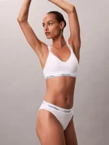 Corpiño Calvin Klein de color blanco, confeccionado en mezcla de algodón y modal. Presenta escote en V, tirantes ajustables y banda elástica inferior con el logo de la marca en contraste.