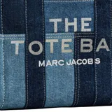Cartera tipo tote bag de Marc Jacobs, confeccionada en denim con diseño de paneles en diferentes tonos de azul. Presenta el logo estampado en el frente, doble asa superior y correa de hombro ajustable y extraíble.