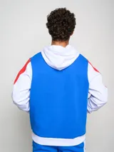 Canguro de felpa Umbro del Club Nacional de Football, con diseño tricolor en rojo, azul y blanco. Presenta capucha con cordones ajustables, bolsillo tipo canguro frontal, logo de la marca y escudo del club bordados en el pecho.
