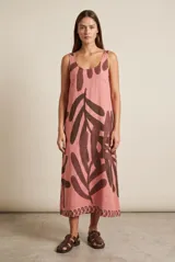 Vestido maxi sin mangas de corte recto, color rosado con gran estampado de hojas en tonos marrones y detalle de guarda en el ruedo. Cuenta con escote redondo y tir Anchos.