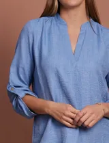 Blusa color beige de poliéster con escote en V y mangas 3/4 regulables con presilla y botón.