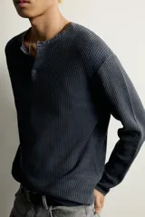 Camiseta relaxed fit de punto negro tejido en hilatura de algodón, con cuello redondo, cierre frontal de botonadura y manga larga con acabado en rib.