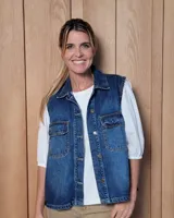 Chaleco de jean azul con cierre frontal de botones metálicos, cuello camisero y dos bolsillos frontales con solapa.