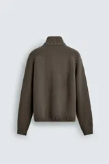 Chaqueta relaxed fit de punto tejido en hilatura con mezcla de algodón, color beige, con cuello subido y manga larga. Cuenta con acabados en rib, efecto lavado y cierre frontal con cremallera.