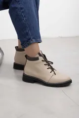 Borcego de cuero vacuno color marrón caramelo con acabado mate, estilo combate y caña baja. Cuenta con cordones marrones, panel de gamuza oscura en el cuello y suela de caucho negra tipo tractor con costura blanca visible.