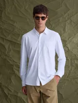 Camisa de manga larga color blanco, con cuello abotonado y bolsillo frontal en el pecho.