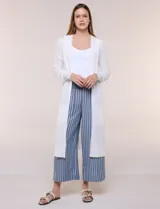 Cardigan largo de punto liviano y suave, de color blanco, con diseño abierto al frente, mangas largas con puños acanalados y bolsillos frontales aplicados.