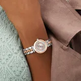 Reloj analógico Guess modelo Leena con caja de 27 mm en tono rose gold y esfera plateada con detalles de cristales. Presenta una correa de acero inoxidable bicolor con eslabones centrales esféricos en tono rose gold y laterales plateados.