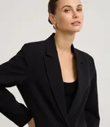 Blazer oversized de crepé color beige, de corte sastre, con solapas de muesca y cierre frontal con un botón.