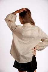 Camisa color crema con bordado de flores blancas, de manga larga abullonada y cuello clásico.