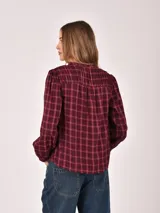 Camisa de manga tres cuartos con cuello mao y cierre frontal de botones. Presenta un diseño a cuadros en tonos oscuros con líneas finas en azul.