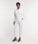 Pantalón jogger blanco de tiro medio/alto con cintura elástica ajustable mediante lazo blanco. Presenta bolsillos laterales y puños ajustados en los tobillos.