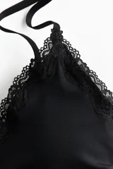 Body negro de punto suave con ribetes de encaje en escote y cavado. Presenta escote en V, breteles ajustables y copas forradas con relleno extraíble. Tiene un refuerzo interior y corte alto en la parte trasera. Diseño sin costuras visibles.