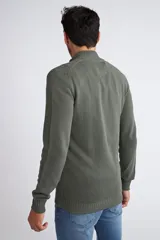 Campera tejida de punto en color verde militar, con cierre frontal completo, cuello elevado y ajuste regular. Presenta un diseño texturizado con logo bordado en el pecho y puños acanalados.