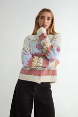 Cardigan de punto con diseño jacquard multicolor, cuello redondo y cierre frontal con botones. Presenta un patrón geométrico y floral en tonos verde, rojo, azul y crema.