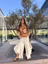 Jean color beige de corte ancho y holgado, con volados laterales pronunciados en las perneras.