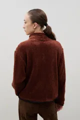 Campera de sherpa color beige con cuello alto, cierre frontal completo y bordado a contra tono en el pecho.