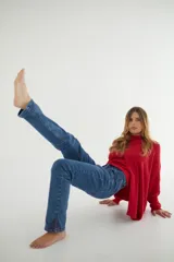 Jean de denim azul elastizado, corte recto y tiro medio, con pespuntes rojos y aberturas en los tobillos.