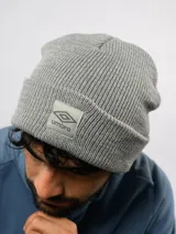 Gorro de lana gris, de punto acanalado con vuelta y parche frontal con el logo de Umbro.